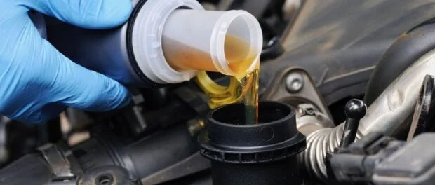 Mechanic doing an oil change on a car Пять ошибок при замене и доливе масла