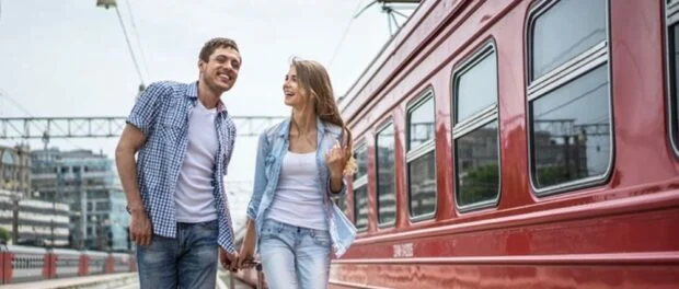 Smiling couple with a suitcase at the train Путешествия на поезде: с чего начать?